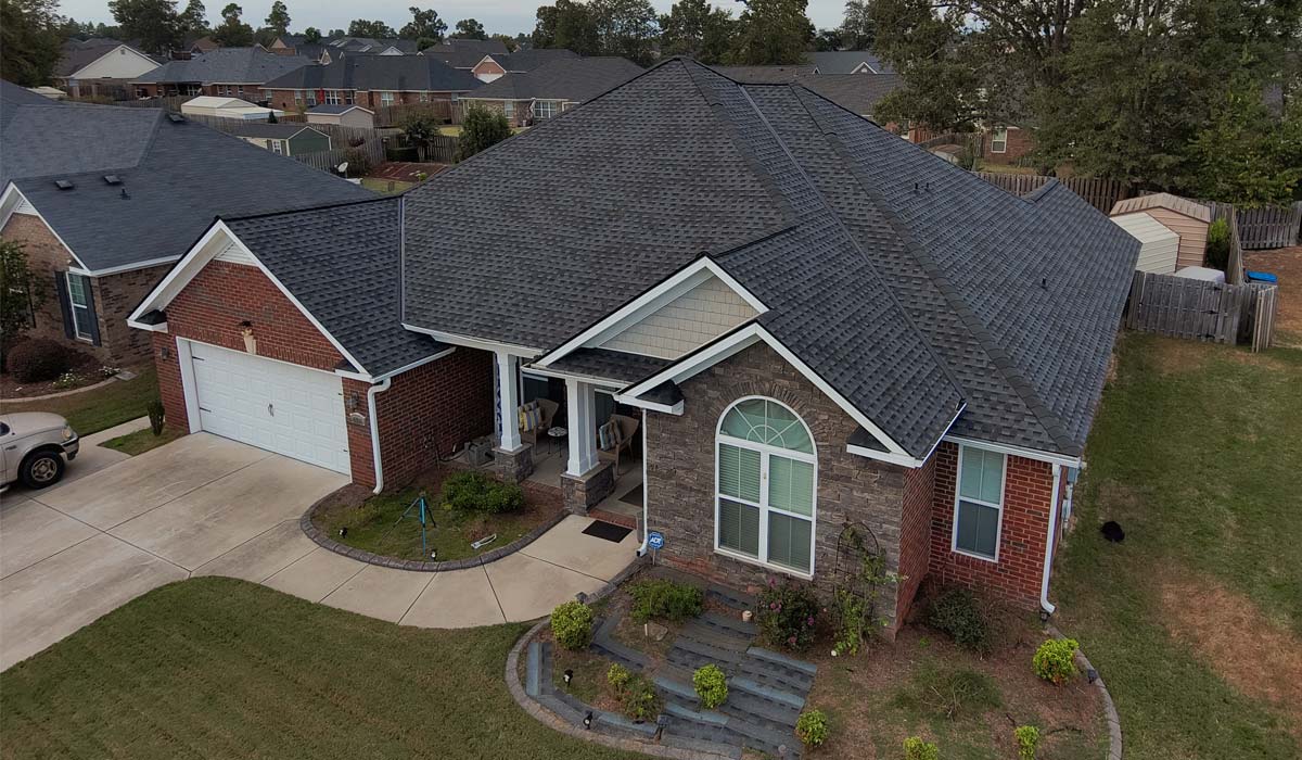 Aerial view of red brick home and shingle roof